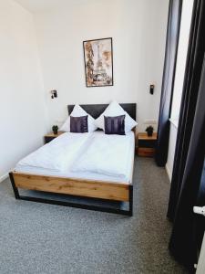 - une chambre avec un lit doté de draps blancs et d'oreillers violets dans l'établissement Best Boarding House, à Hanau