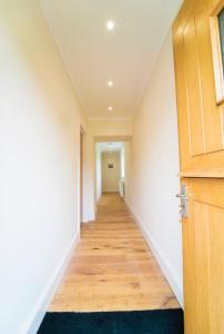 um corredor com paredes brancas e uma porta de madeira em Foundry Farm Cottage em Hexham
