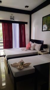 エルニドにあるLolo Panding Innの赤いカーテンが備わるドミトリールームのベッド2台分です。