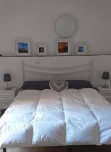 a white bed in a bedroom with two lamps and a mirror at Residenza Solferino in Corniglia