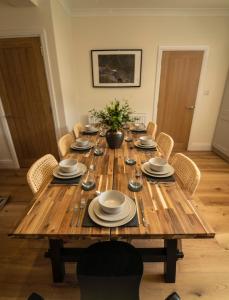 uma mesa de madeira com cadeiras e pratos em Foundry Farm House em Hexham