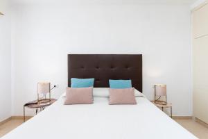 sypialnia z dużym białym łóżkiem z niebieskimi i różowymi poduszkami w obiekcie OLIVIA SUNSET Perfect Stay by Sunkeyrents w mieście Puerto de Santiago