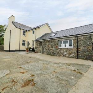 an old stone house with a driveway in front of it at Gwlgri in Holyhead