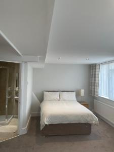 a white bedroom with a bed and a window at Aabba Guest House in Whitley Bay