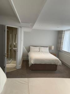 um quarto branco com uma cama e uma janela em Aabba Guest House em Whitley Bay