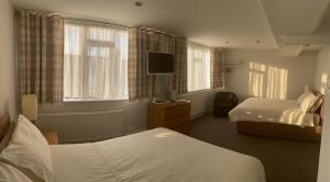um quarto de hotel com duas camas e uma televisão em Aabba Guest House em Whitley Bay