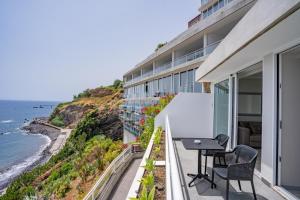 um apartamento com varanda com mesa e cadeiras com vista para o oceano em Hotel Orca Praia no Funchal