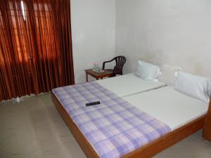 a bedroom with a bed with a remote control on it at R M Guest House in Kālapettai