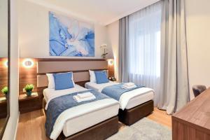 Habitación de hotel con 2 camas y almohadas azules en Hotel Opera Garni en Belgrado