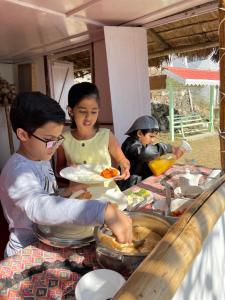 un gruppo di bambini seduti a un tavolo che mangiano cibo di THE GINGKO EYRIE a Kalimpong