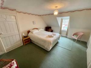 a bedroom with a white bed and a pink chair at The Nook, Morebattle. in Morebattle