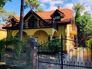 a yellow house with a black fence at Villa B96 Siófok in Siófok