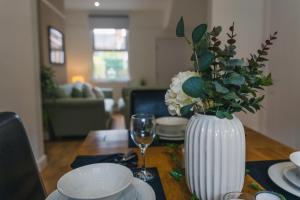 einen Tisch mit einer weißen Vase mit Blumen darauf in der Unterkunft Villiers House - Comfy Stylish Home in Leamington Spa