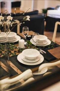 stół z białymi talerzami i kieliszkami do wina w obiekcie Northum Place - Elegant City Centre Apartment w mieście Leamington Spa