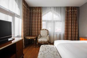 a room with a bed, chair and television at Sheki Palace Hotel in Sheki