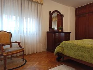 a bedroom with a bed and a chair and a mirror at APARTAMENTO MARRODAN CENTRICO in Arnedillo