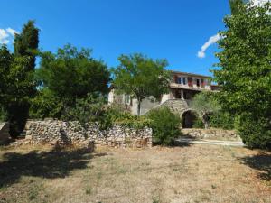 an old stone house with a stone wall and trees at Le Gite du Gamin in Vagnas