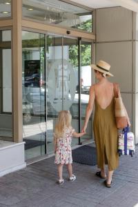 una mujer sosteniendo la mano de una niña fuera de una tienda en Astoria, en Tesalónica
