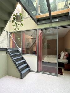 une maison en verre avec un escalier et un lit dans l'établissement Maison exceptionnelle, Campagne a Paris, à Paris