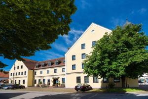 un gran edificio blanco con un árbol delante en Hotel Gumberger GmbH Garni, en Neufahrn bei Freising