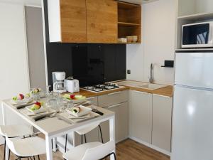 cocina con mesa blanca y electrodomésticos blancos en Camping Pleine Mer en Vias