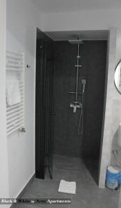 baño con ducha y puerta de cristal en Black & White - News Apartment, en Bucarest