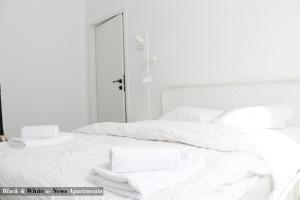 uma cama branca com lençóis brancos e toalhas em Black & White - News Apartment em Bucareste