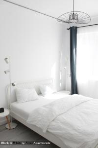 a bedroom with a white bed and a window at Black & White - News Apartment in Bucharest