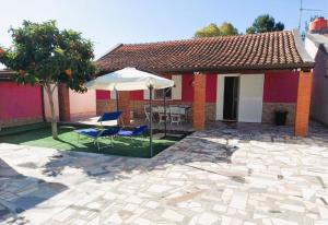 a patio with an umbrella and chairs and a house at New Summer Apartment in Agnone Bagni