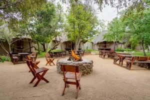 a group of tables and chairs and a fire pit at Warthogs Bush Lodge in Magaliesburg