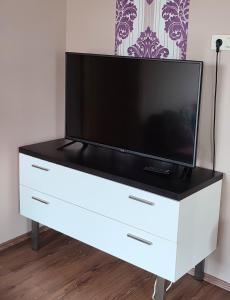a white dresser with a television on top of it at Aqua Apartmanok in Pécs
