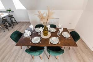 a dining room table with green chairs and a wooden floor at BOURNECOAST: STYLISH FLAT WITH BALCONY - SEA VIEWS - PARKING - WIFI - FM8407 in Southbourne