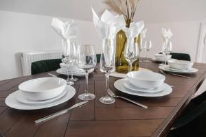 a wooden table with plates and wine glasses on it at BOURNECOAST: STYLISH FLAT WITH BALCONY - SEA VIEWS - PARKING - WIFI - FM8407 in Southbourne