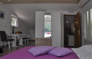 1 dormitorio con cama con almohadas moradas y escritorio en Apartment Danijela en Okuklje