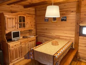 a log cabin kitchen with a table and a tv at chalet le balcon du Sancy - location du samedi au samedi - linge de lits fournis - option ménage fin de séjour non proposée in Le Mont-Dore