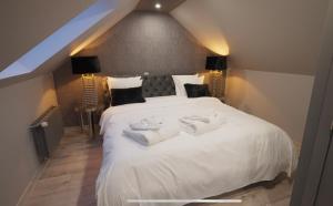 Les Suites M في Wanze: غرفة نوم بسرير ابيض كبير عليها مناشف