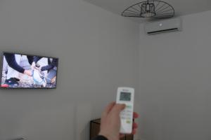 una persona con un control remoto frente a un televisor en Black & White - News Apartment en Bucarest