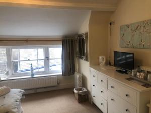 a bedroom with a dresser with a television and a window at Wayfarer Inn in Instow