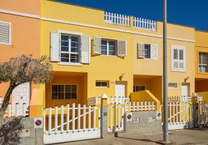a yellow building with a white fence in front of it at DUPLEX EN EL CENTRO DE GALDAR in Gáldar