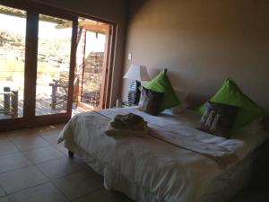 a bedroom with a large bed with green pillows at Plato Lodge in Augrabies
