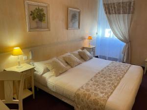 a bedroom with a large white bed with two lamps at Le Grand Hôtel in Souillac
