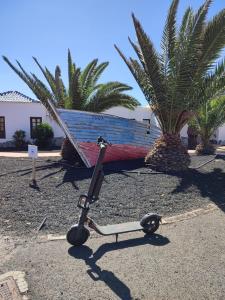 uno scooter è parcheggiato di fronte a una barca. di Apartment El Barco - Las Casas de Aron a Caleta De Fuste