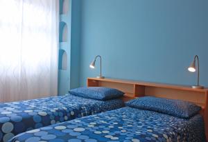 two beds in a room with blue walls at Edera Residence in Trieste