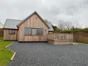a wooden house with a gravel driveway in front of it at Osprey Lodge 8 with Hot Tub in Newton Stewart