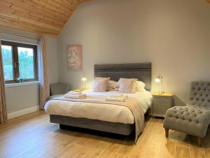a bedroom with a large bed and a chair at Osprey Lodge 8 with Hot Tub in Newton Stewart