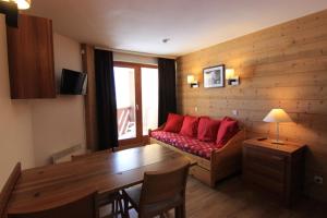 a living room with a red couch and a table at Temples du Soleil Machu Appartements VTI in Val Thorens