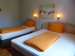 two beds with orange pillows in a room at Haus der Gastlichkeit in Ratingen +7 photos
