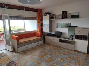 sala de estar con sofá naranja y ventana en Punta Ala Top apartment, en Punta Ala