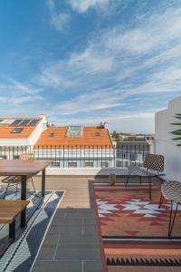 Un patio con mesas y sillas en un tejado. en Casa Boma Lisboa - Sunny Apartment with Private Balcony and Panoramic Bridge View - Ajuda I, en Lisboa