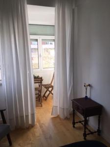 ein Wohnzimmer mit weißen Vorhängen und einem Tisch in der Unterkunft Charming Suite Private Wc & Balcony in Lissabon